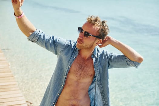 In sunglasses. Young european man have vacation and enjoying free time on the beach of sea.