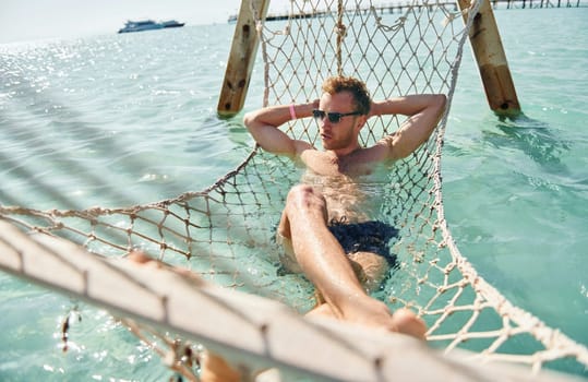 In sunglasses. Young european man have vacation and enjoying free time on the beach of sea.