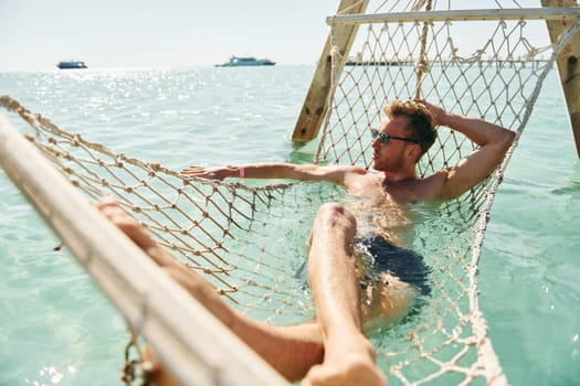 In sunglasses. Young european man have vacation and enjoying free time on the beach of sea.