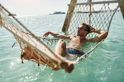 In sunglasses. Young european man have vacation and enjoying free time on the beach of sea.