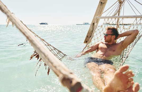 In sunglasses. Young european man have vacation and enjoying free time on the beach of sea.