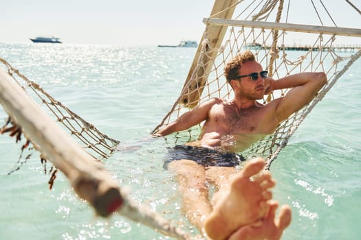 In sunglasses. Young european man have vacation and enjoying free time on the beach of sea.