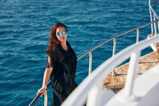 Mature woman standing on the yacht and enjoying her vacation on the sea.