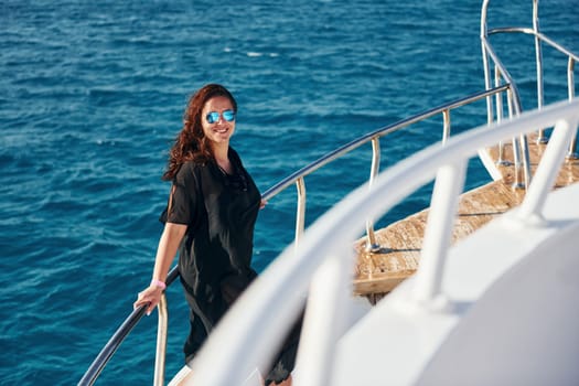 Mature woman standing on the yacht and enjoying her vacation on the sea.