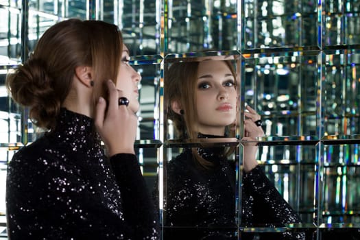 Full length portrait of beautiful young woman in long black dress near mirror