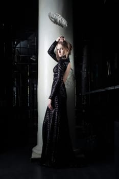 Full length portrait of beautiful young woman in black dress near column