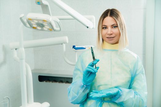 The dentist holds an injection syringe for the patient in the office.