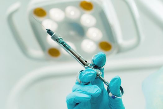 close-up of a dentist's hand holding an injection syringe for a patient in the office.