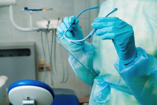 close up of a dentist's hands holding a protective plastic screen in his office.