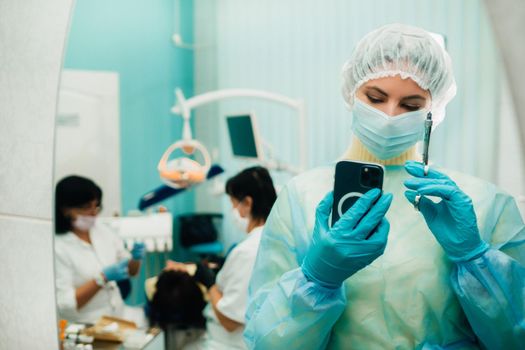 the dentist in a protective mask stands next to the patient and takes a photo after work.