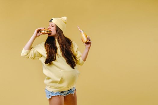 pregnant girl in yellow clothes with hamburgers in her hands on a yellow background.