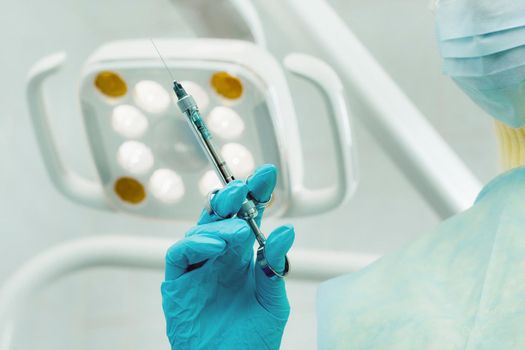 close-up of a dentist's hand holding an injection syringe for a patient in the office.
