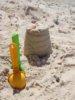 Set of color plastic children toys on sand near sea. Beach object. A close up of a sand castle on a sandy beach near the sea.