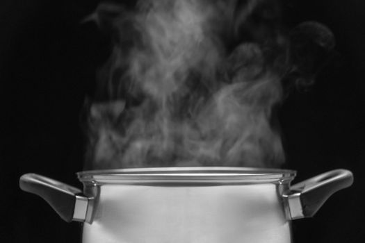 steam over cooking pot in kitchen on dark background