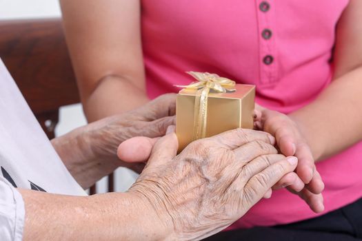 Elderly woman receiving a gift from daughter