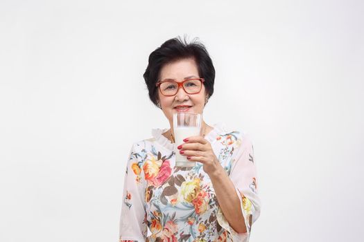 Senior woman holding a glass of milk , isolated on white background.