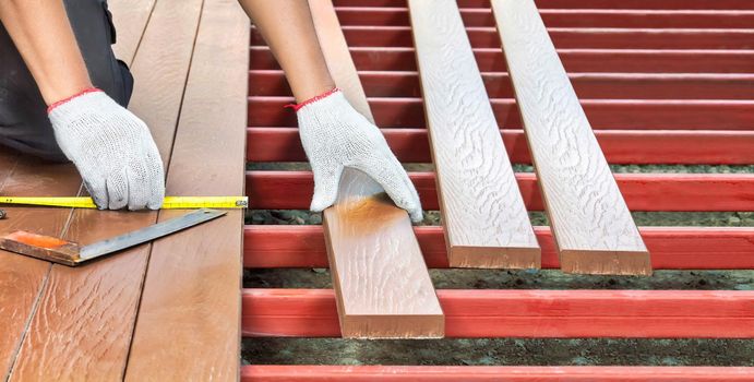 Worker installing wood floor for patio