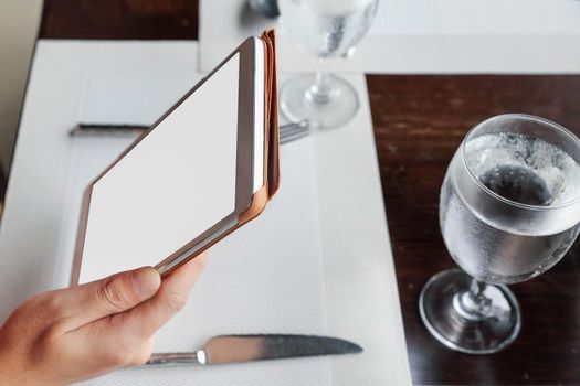 woman sitting using a tablet on dining table in restaurant