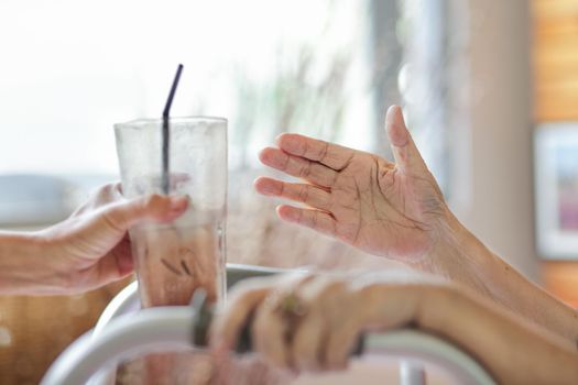 Elderly woman get a glass of ice cocoa from caregiver.