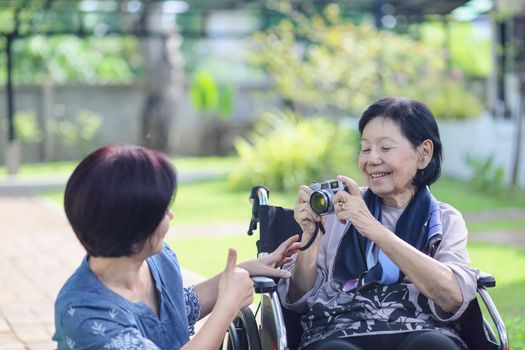 Son and daughter in law looking after elderly mother in backyard