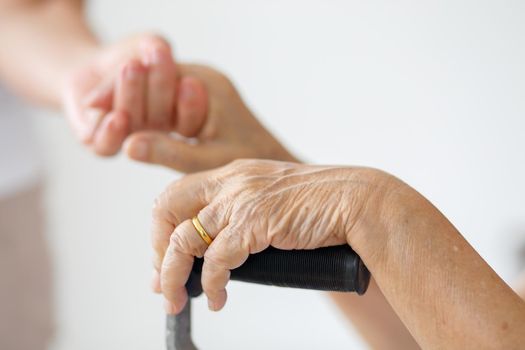 Elderly asian woman using a cane at home with caregiver take care