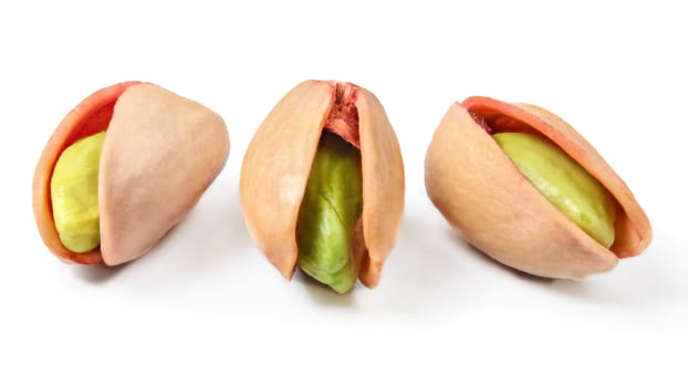 Three red turkish pistachios, peeled green nuts visible in cracked shells isolated on white background.