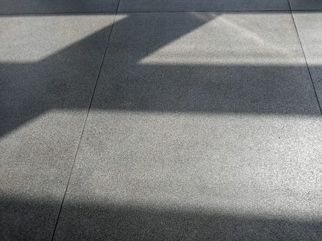 Shadows from morning sun on concrete airport waiting hall floor. Abstract natural light vs artificial material background.