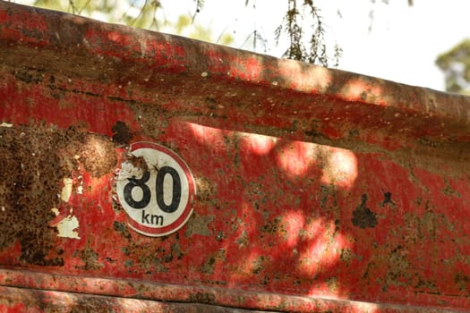 Detail on speed limit 80 km/h sign at the rear of old dump truck cargo container.