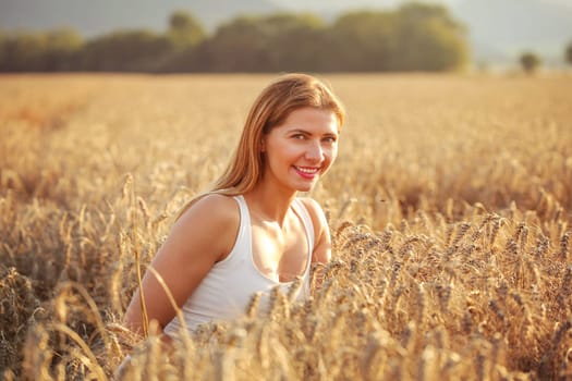 Young woman in wheat field lit by afternoon sun.