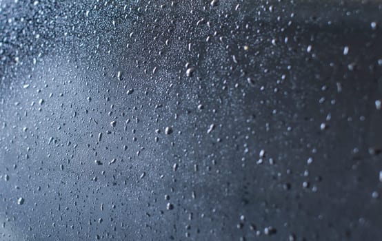 Rear of car wet after being washed in carwash. Abstract "drops of water on glass" background.