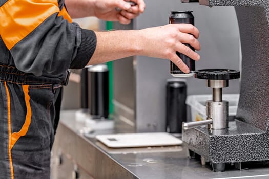 closed with the lid of beverage cans in an automatic capping machine in a brewery.