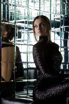 Full length portrait of beautiful young woman in long black dress near mirror