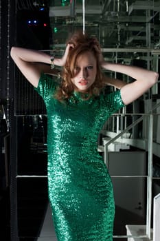 Full length portrait of young aggressive woman in green fashion dress in nightclub
