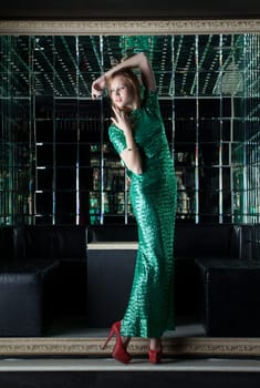 Young red woman in fashion green dress - mirror room of nightclub