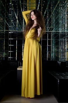 Full length portrait of pretty brunette woman in long fashion dress -- night club interior