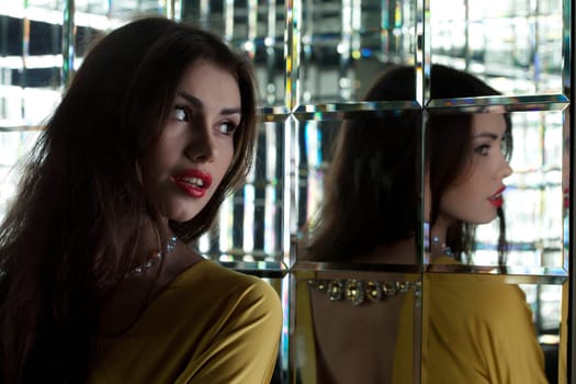 Portrait of young beautiful brunette woman near mirror