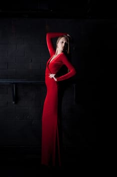 Full length portrait of beautiful woman in red long dress in dark club
