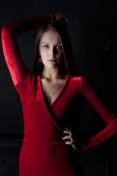 Portrait of beautiful young woman in red dress in dark room