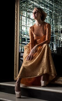Charming blonde posing in fashionable golden dress