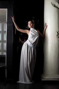 Portrait of pretty brunette young woman near column in fashion cloth