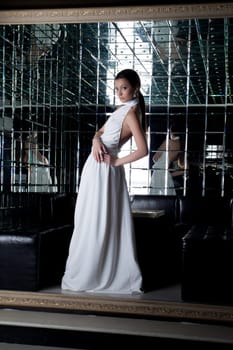 Full length portrait of brunette woman in white dress in club