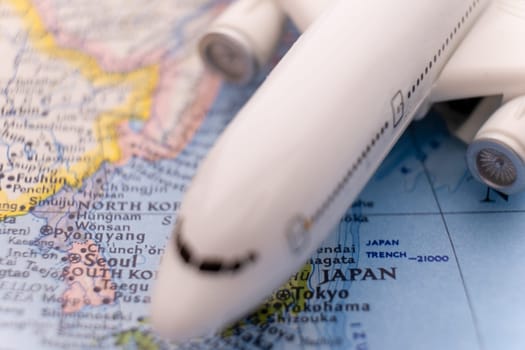 Close up detail of a miniature passenger airplane on a colorful map focusing on Tokyo Japan through selective focus, background blur.