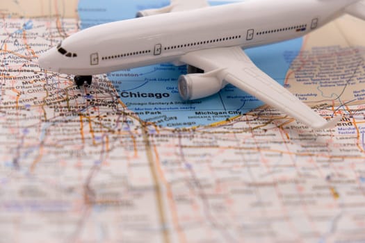 Miniature passenger airplane on a detailed colorful map focusing on Chicago, Illinois through selective focus, background blur