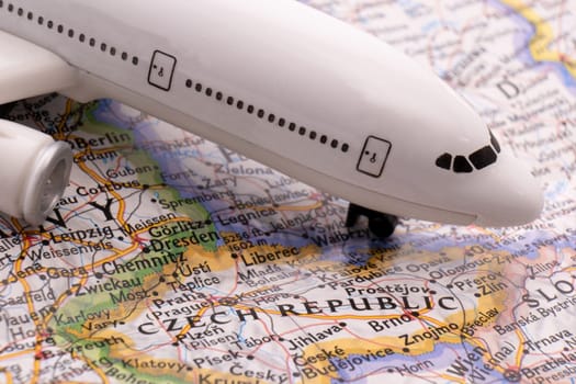 Close up detail of a miniature passenger airplane on a colorful map focusing on Czech Republic through selective focus, background blur.