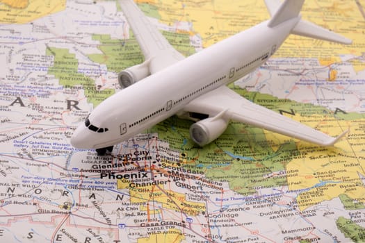 Close up detail of a miniature passenger airplane on a colorful map focusing on Phoenix, Arizona through selective focus, background blur.