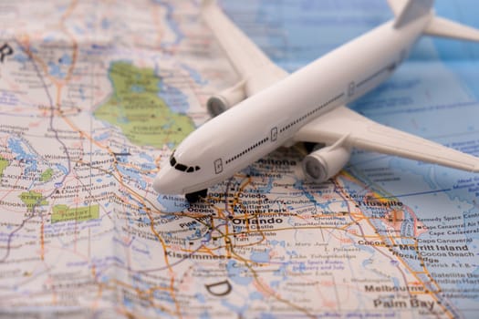Close up detail of a miniature passenger airplane on a colorful map focusing on Orlando, Florida through selective focus, background blur.