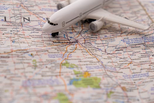 Miniature passenger airplane on a colorful map focusing on Indianapolis, Indiana through closeup selective focus, background blur. High quality photo
