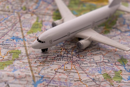 Close up detail of a miniature passenger airplane on a colorful map focusing on Atlanta Georgia through selective focus, background blur.
