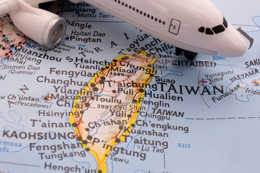 Close up detail of a miniature passenger airplane on a colorful map focusing on Taiwan through selective focus, background blur.