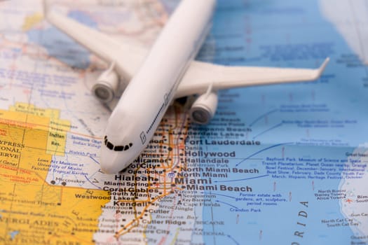 Passenger plane on a map highlighting Miami, Florida through selective focus on text of map, background blur. High quality photo